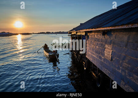 Tonlé Sap Lake,  Cambodia. 17th December, 2018.  A woman paddles her boat away from her floating home into the sunset.  Photo: Bryan Watt Stock Photo