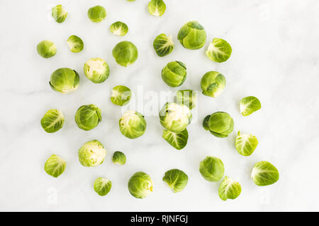 Top view of raw brussels sprouts scattered on white marble background. Stock Photo