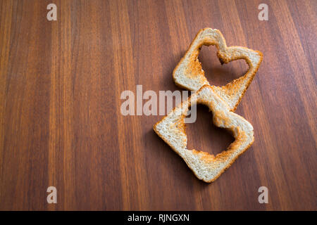 Toasted white bread toasts with heart shape on brown wooden background, love, valentines day Stock Photo