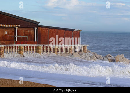 Rough sea in winter in Porto Recanati in the province of Ancona Italy near Monte Conero with the sea crashing on rocks and a boarded up restaurant Stock Photo