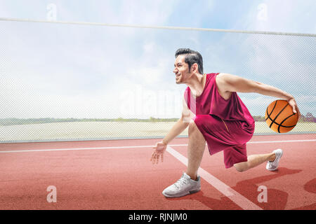 Handsome asian basketball player man playing basketball on the basketball court Stock Photo