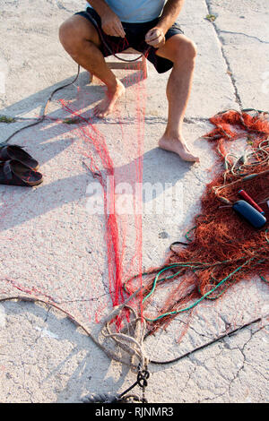 Fisherman repairing fishing net on the shore Stock Photo