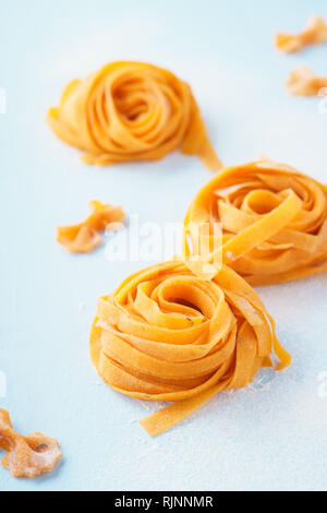 Uncooked homemade vegan pasta on light blue background. Ingredients for healthy eating. Stock Photo