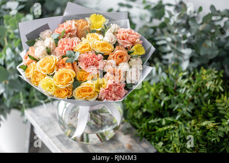 beautiful fresh cut bouquet of mixed flowers in vase on wooden table. The work of the florist at a flower shop. Delicate Pastel tones color Stock Photo