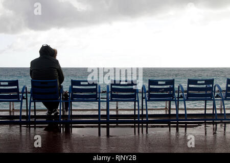 Lone person sitting on a chair at the coast of Nice, France Stock Photo