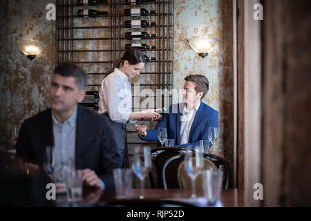 Waitress taking payment in a restaurant Stock Photo