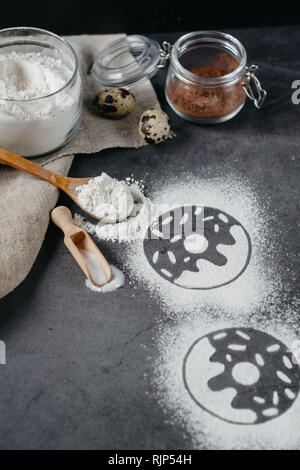 Ingredients for donuts baking. Spoon with flour, dishes, eggs, sugar on a grey background. Top view, copy space. Bakery background frame. Stock Photo