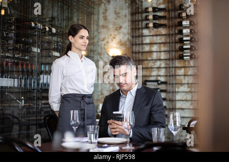 Waitress taking payment in a restaurant Stock Photo