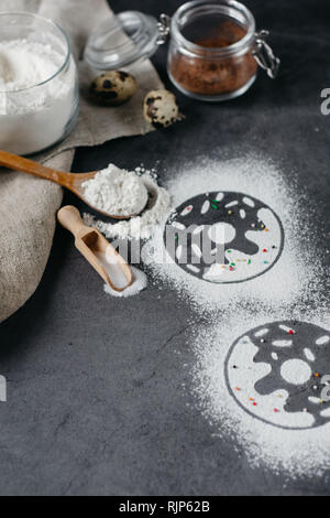 Ingredients for donuts baking. Spoon with flour, dishes, eggs, sugar on a grey background. Top view, copy space. Bakery background frame. Stock Photo