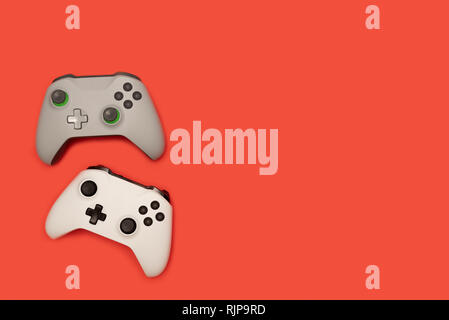Two game pads isolated on red background. Video gaming concept. Stock Photo