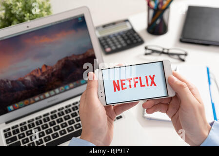 Wroclaw, Poland - JAN 31, 2019: Man holding smartphone with Netflix logo. Netflix is a global provider of streaming movies and TV series Stock Photo