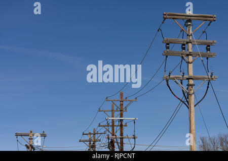 Electrical power grid, row of utility poles and high voltage power lines against a blue sky in South Dakota, USA Stock Photo