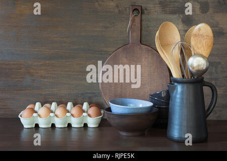 Crockery, clayware, dark utensils and other different stuff on wooden tabletop. Kitchen still life. Stock Photo