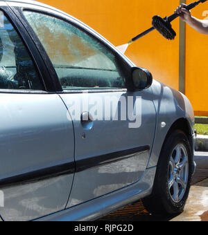 Man washing windshield from foam with high pressure jet washer Stock Photo