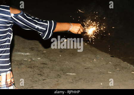 Sparklers on hand on black background on a low light evening. Selective focus on sparklers. Mother, Daughter, Woman, Lady, girl, kid, child holding sp Stock Photo