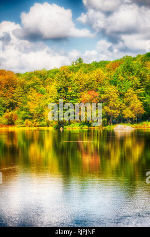 Fall foliage in autumn reflecting against the waters of Burr Pond State Park in Torrington Connecticut on a sunny blue sky day. Stock Photo