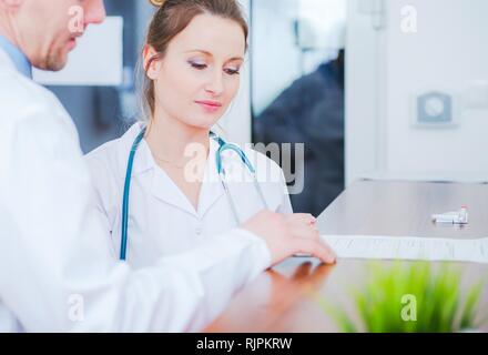 Caucasian Female Medical Worker in White Lab Coat Making Conversation with Doctor. Healthcare Industry. Stock Photo