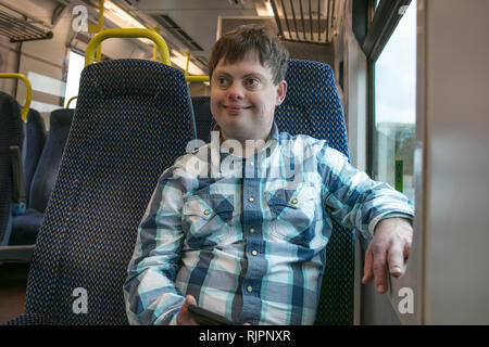 Man with down syndrome with cell phone on train Stock Photo