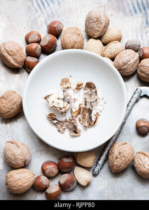 Walnuts and almonds in shell, hazelnuts, cracked walnut in bowl Stock Photo