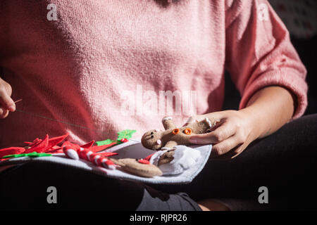 Woman stitching felt gingerbread man onto christmas decoration, mid section Stock Photo