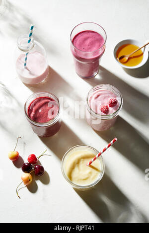 Fruit and yogurt smoothies in glass bottle and jars, overhead view Stock Photo
