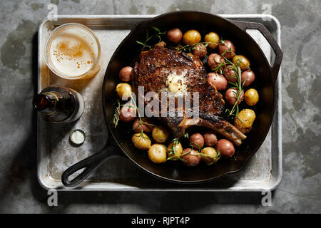 Skillet with large tomahawk steak & potatoes, overhead view Stock Photo