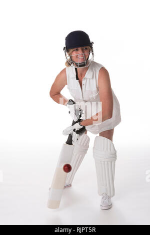 Woman cricketer in a white dress with a safety helmet, shin pads, a bat and ball. Stock Photo