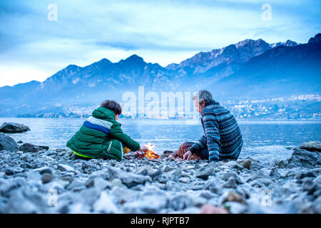 Father and son starting campfire, Onno, Lombardy, Italy Stock Photo