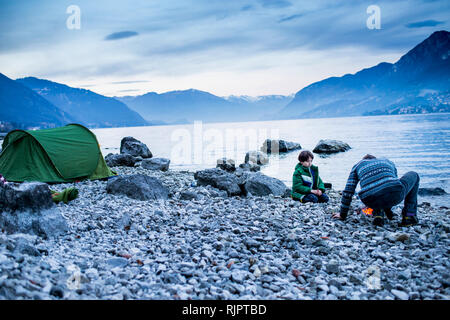 Father and son starting campfire, Onno, Lombardy, Italy Stock Photo