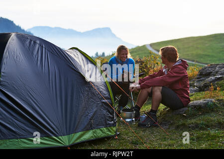 Hikers relaxing by tent, Manigod, Rhone-Alpes, France Stock Photo