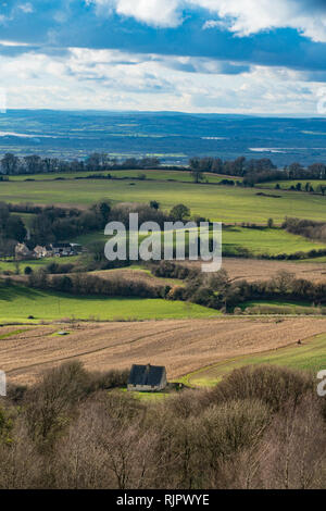 View from the summit of Painswick Beacon in the Cotswolds, Goucestershire, UK. Standing on the hill fort looking out across fields and cottages to the Stock Photo