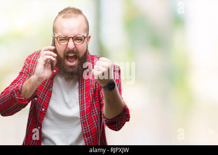 Young caucasian hipster man talking on smartphone over isolated background annoyed and frustrated shouting with anger, crazy and yelling with raised h Stock Photo