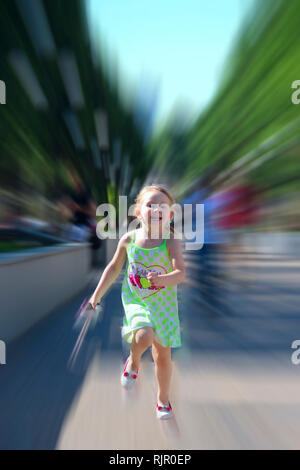 Happy little girl running in city park. Positive childish emitions. Child running along path smiling and rejoicing. Happy childhood. Child running wit Stock Photo