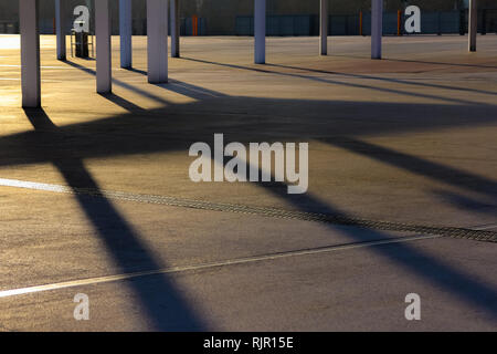 Modern architecture shadows on the ground back lit by warm evening sun. Sunset shadow Stock Photo