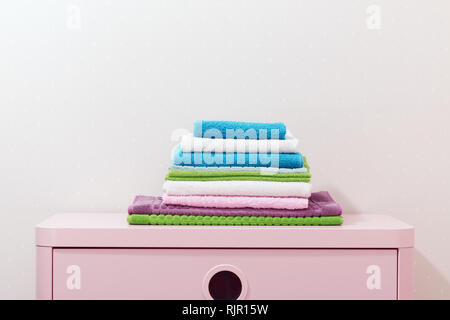 On the chest lies a stack of stacked colorful towels. Stock Photo