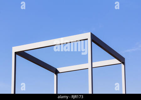 Close up outdoor view of a metallic cube structure made of iron. Pattern of blue crossing lines with a blue sky in background. Geometric design with p Stock Photo