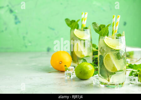Two mojito cocktails with lime and mint in highball glasses on a gray and green concrete stone surface background. With copy space for your text Stock Photo