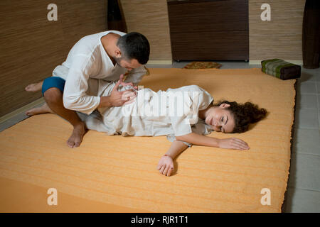 Tibetan massage. The massage therapist makes a Tibetan massage to a young woman. man and woman in white doing gymnastics Stock Photo