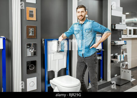 Portrait of a man as a seller or repairman in the plumbing shop with bowl buttons for draining on the background Stock Photo