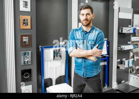 Portrait of a man as a seller or repairman in the plumbing shop with bowl buttons for draining on the background