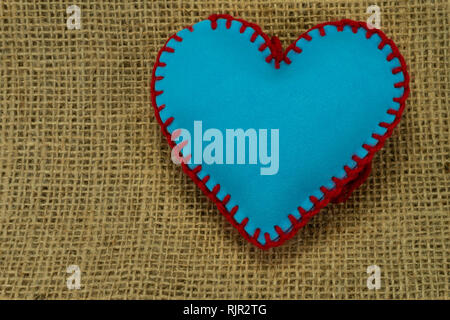 Valentine Day template, one handmade blue foam sheet stitched toy heart on jute canvas, close up, high angle view. Love, relationship, Valentines Day, Stock Photo