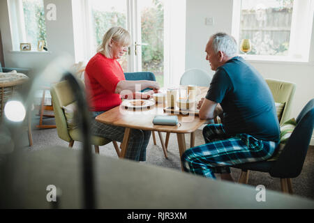 Mature couple are having breakfast together at the dining table in their home. Stock Photo