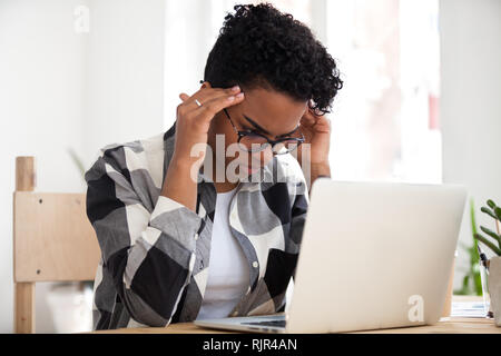 Stressed african woman concentrating doing difficult online computer work Stock Photo
