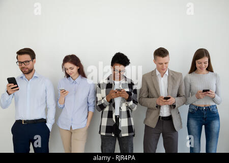 Millennial phone users businesspeople group standing in row using smartphones Stock Photo
