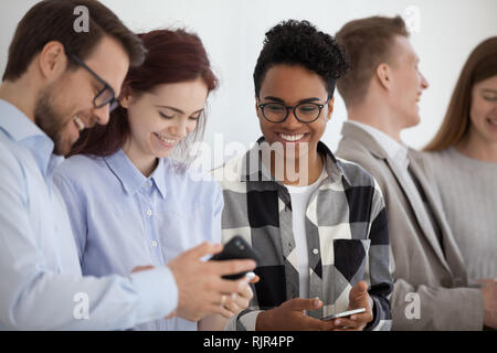 Smiling multi-ethnic people holding phones having fun with mobile devices Stock Photo