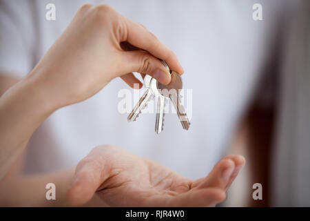 Broker hand holding keys giving to new home owner, closeup Stock Photo