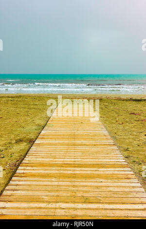 Minimalistic view of sandy beach with wooden path and sea horizon Stock Photo