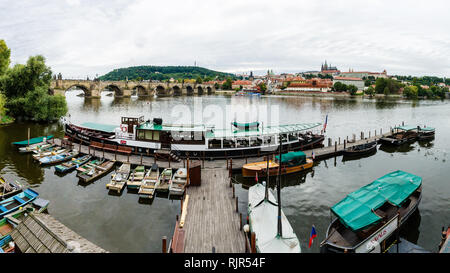Boat dock on Vltava river next to Charles bridge with Castle District, St. Vitus cathedral and Petrin hill in the background, Prague, Czech Republic Stock Photo