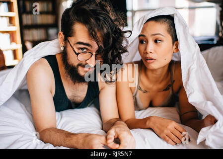 Happy couple under covers in bed Stock Photo