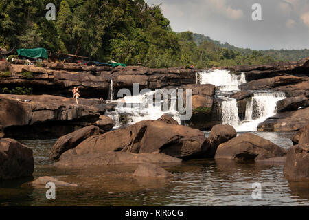 Cambodia, Koh Kong Province, Tatai, Waterfall, tourists on rocks amongst water flowing over falls in dry season Stock Photo